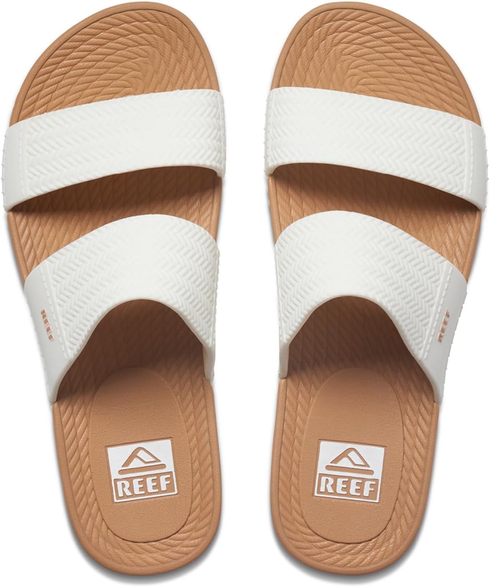 Tan and white slide sandals with textured straps and REEF stamped footbeds