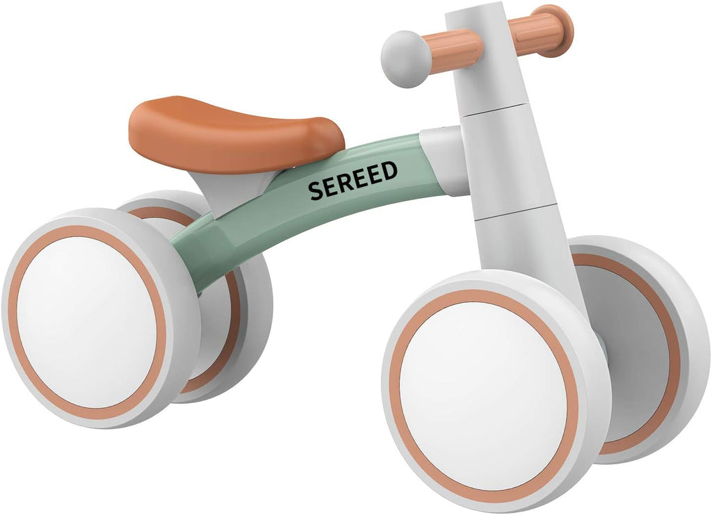 Close view of green-frame toddler balance bike with orange seat, white wheels, and grips