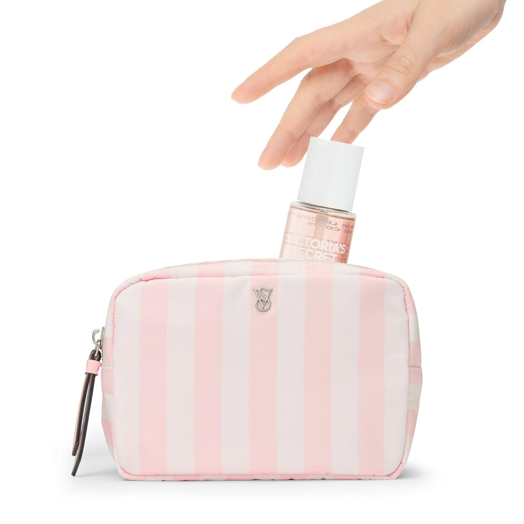 Mini fragrance mist bottle held above a pink striped toiletry pouch.
