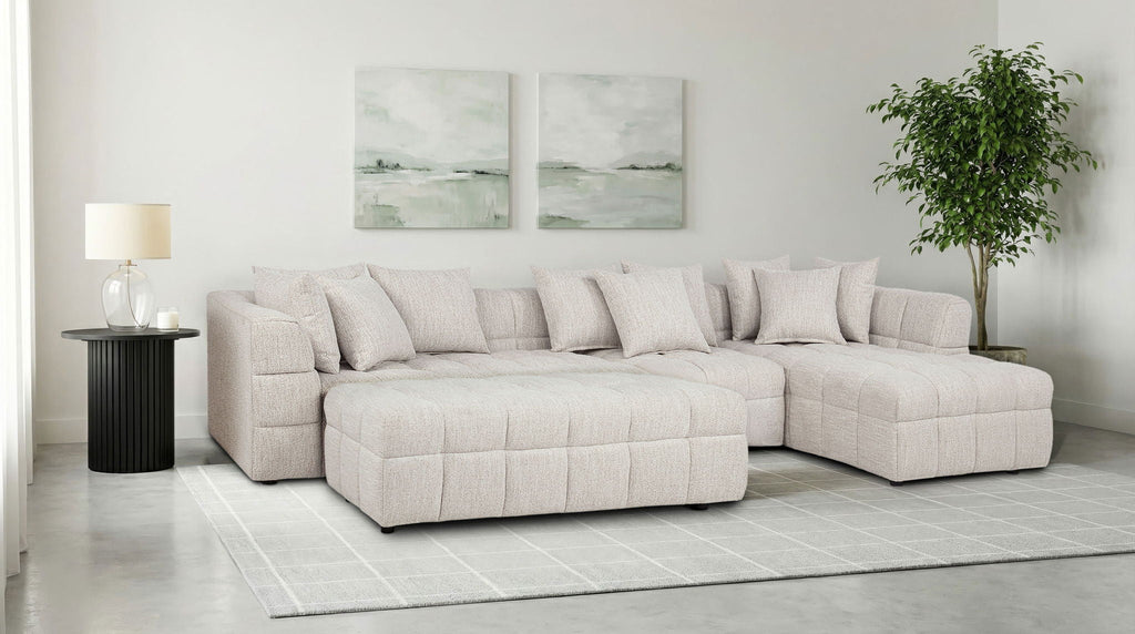 Light beige upholstered sectional sofa with rounded chaise and multiple back cushions