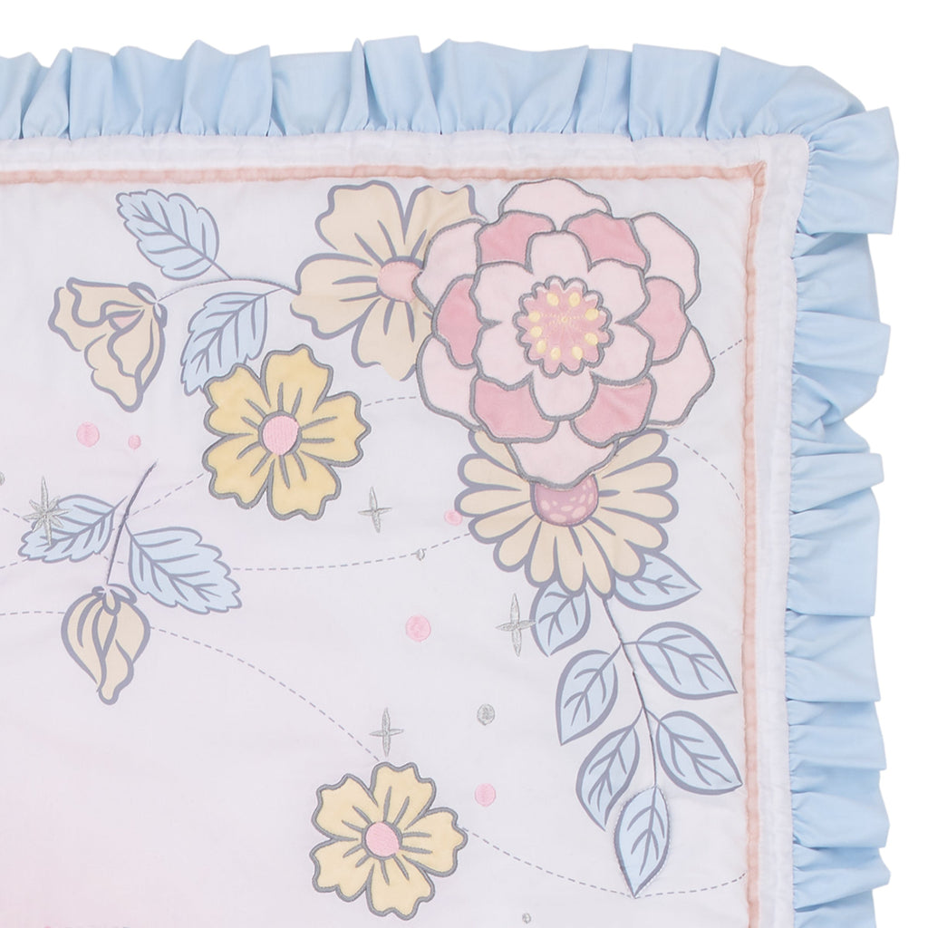 Crib skirt fabric with large pastel flowers, leaves, and light blue ruffle border