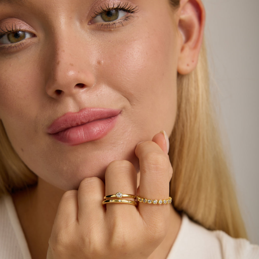 Gold ring with round bezel stone, worn on finger