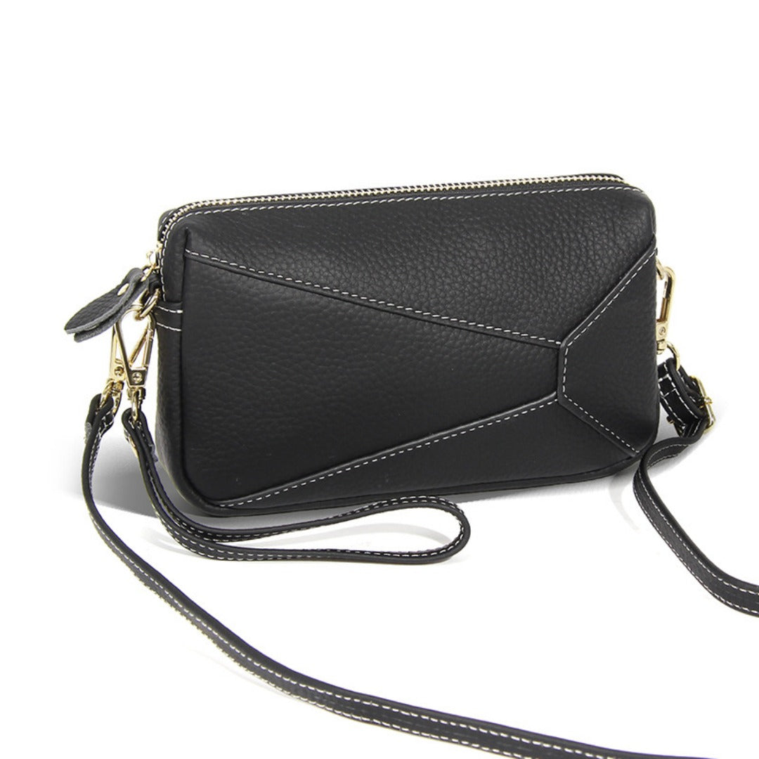 Black leather crossbody wristlet bag with gold-tone hardware and zip closure
