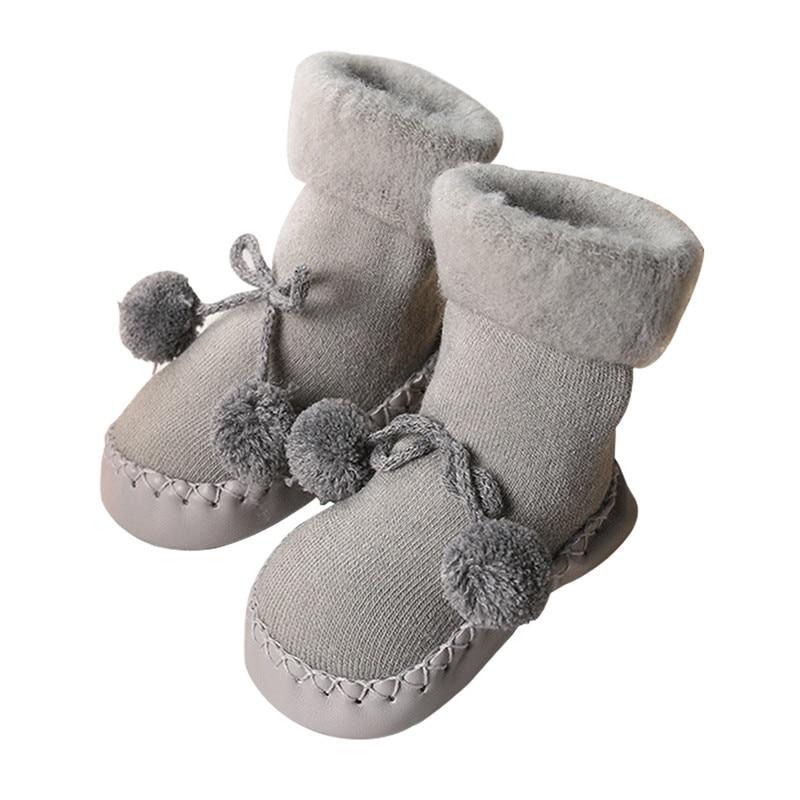 Pair of baby socks in light grey with pom-pom bows and lace-up detail