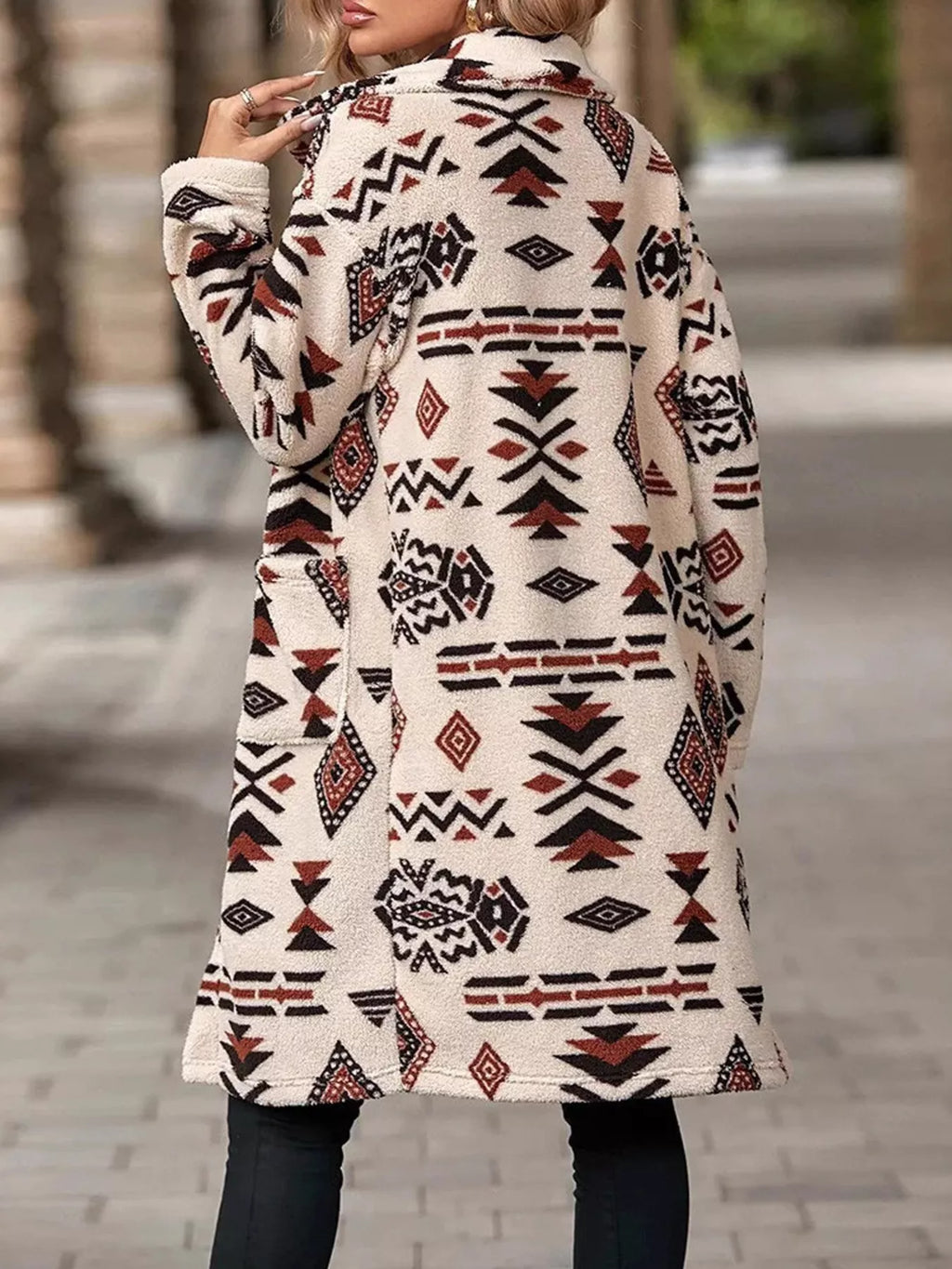 Back view of geometric longline button-up coat, cream with red and black motifs.