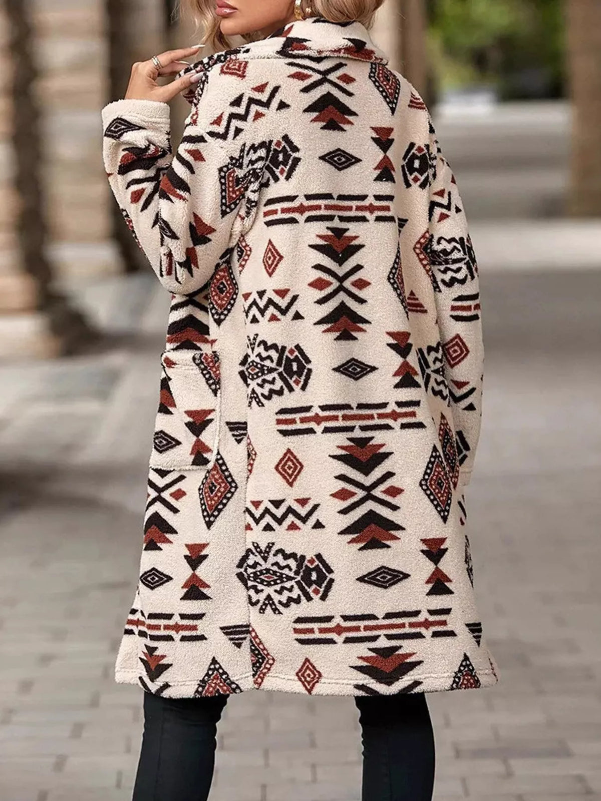 Back view of geometric longline button-up coat, cream with red and black motifs.