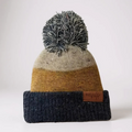 Two-tone puff knit beanie in mustard yellow with dark pom-pom and leather logo patch