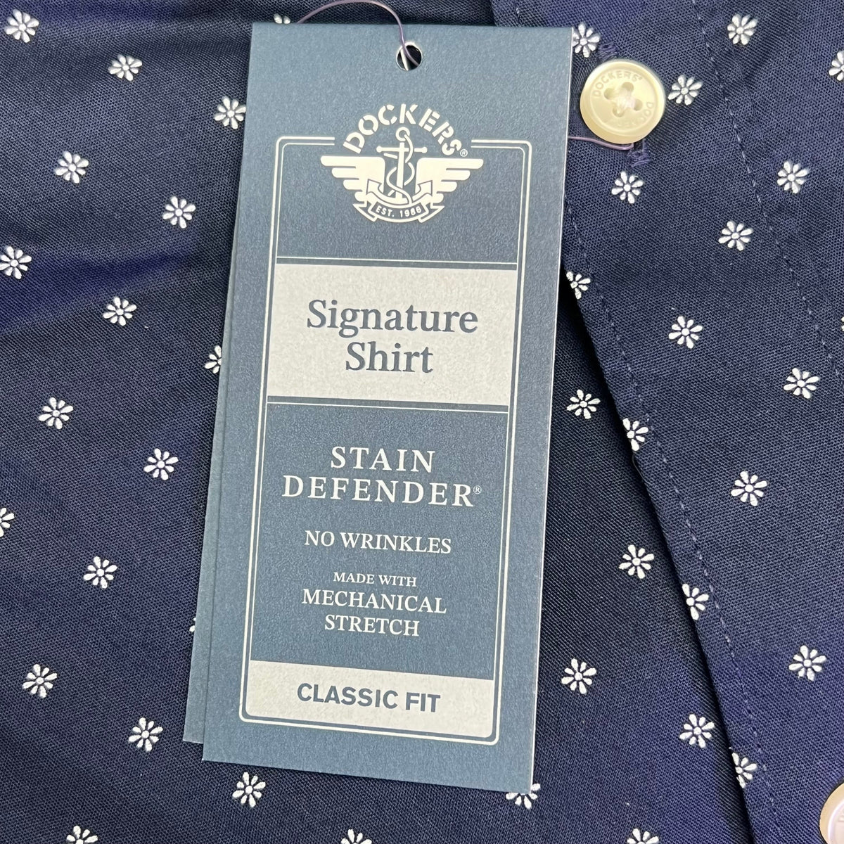 Close-up hang tag: Signature Shirt Stain Defender, no wrinkles, mechanical stretch, classic fit