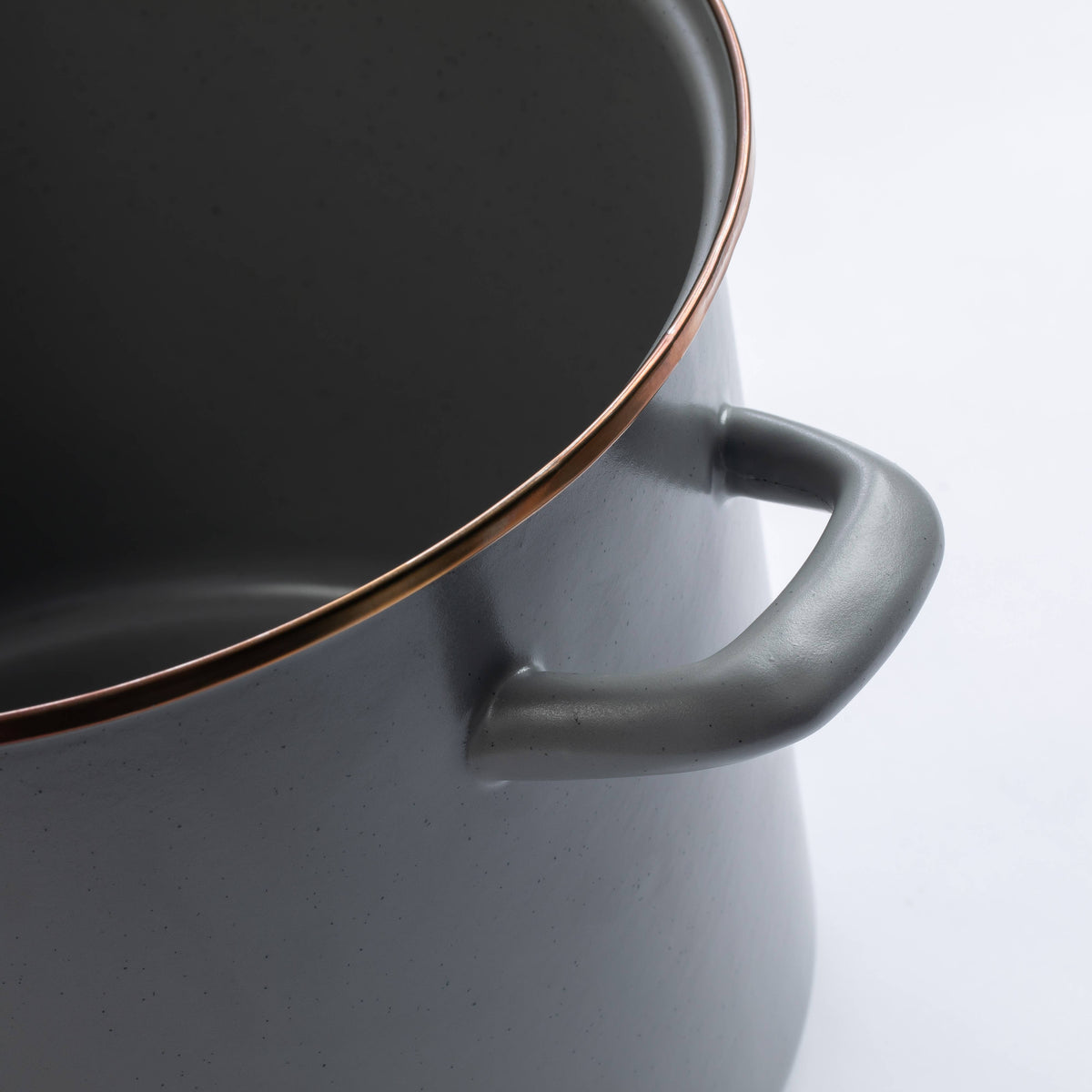 Enamel stock pot close-up of side handle and rim, dark gray enamel with copper trim