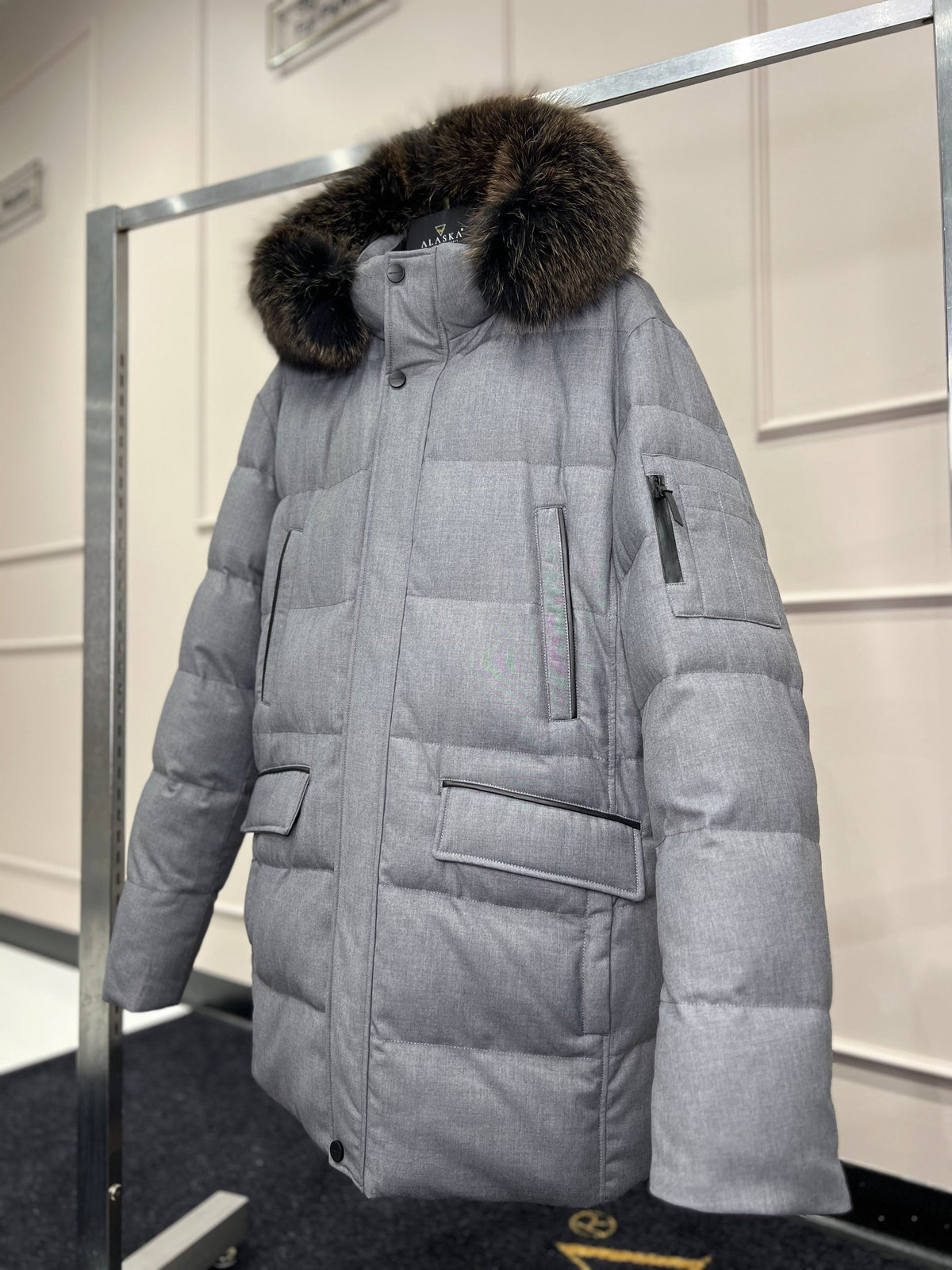 Men's grey puffer coat with dark fur-trim hood and chest pocket with flap