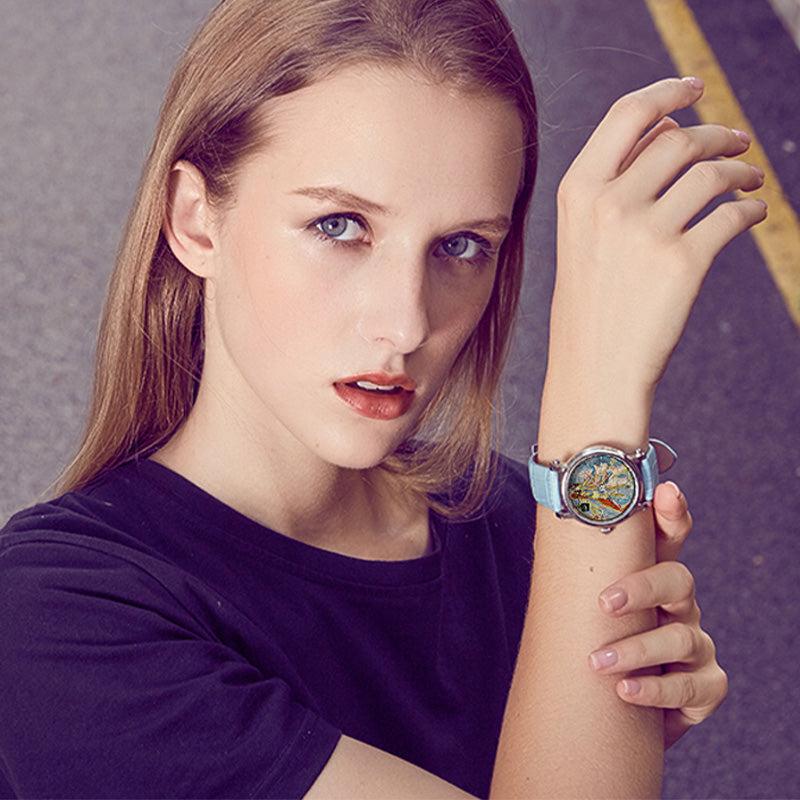 Quartz wristwatch on wrist with blue strap and rose-gold case, round colorful art dial