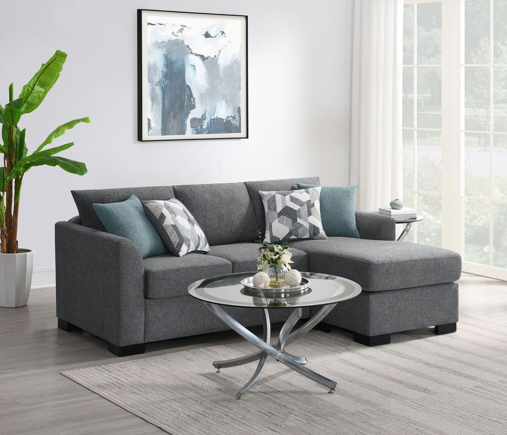 Grey sectional chaise sofa with teal accent pillows and geometric patterned cushions