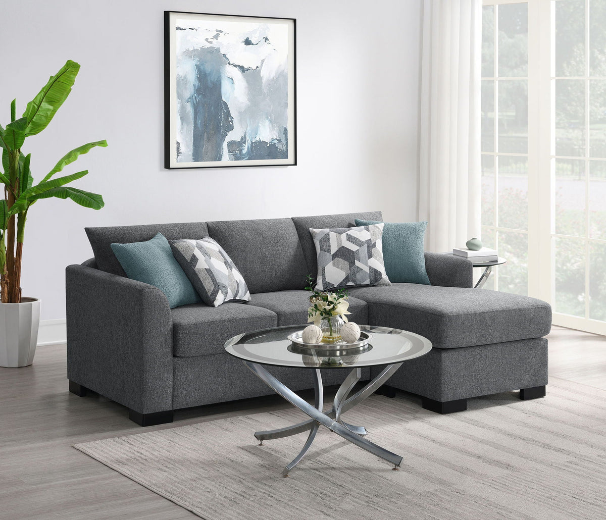 Grey sectional chaise sofa with teal accent pillows and geometric patterned cushions