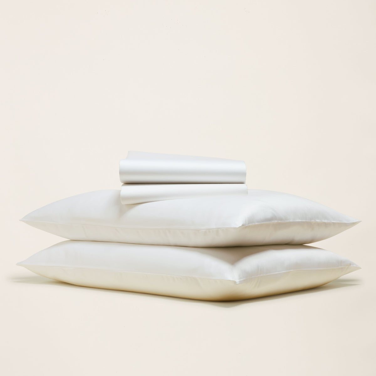 Ivory sateen sheet set with folded pillowcases and flat sheet, neatly stacked