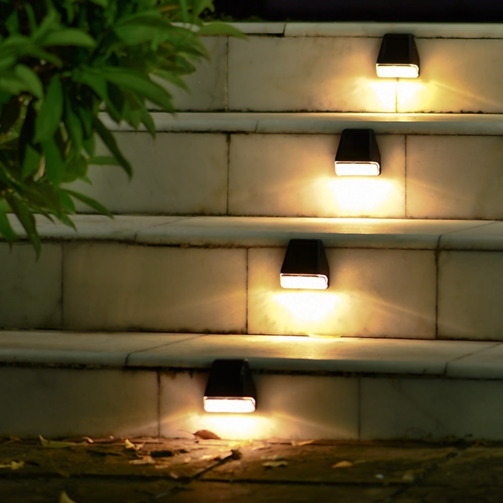 Solar LED wall lamps mounted on a wall, emitting warm light from square caps