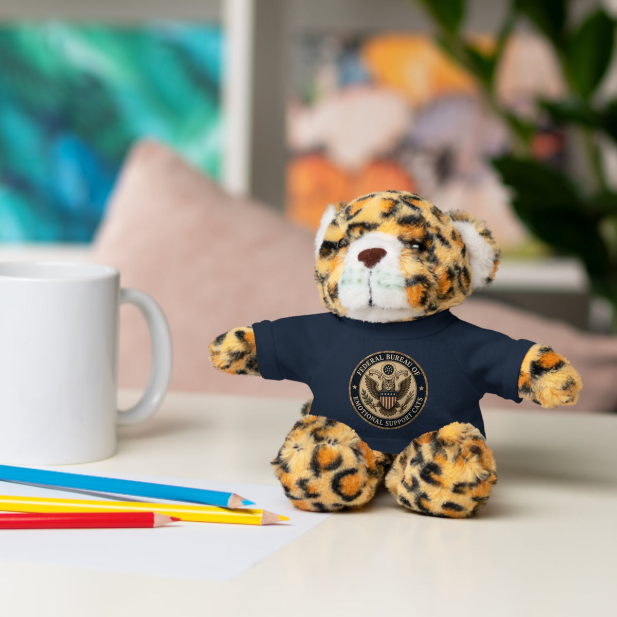 Jaguar plush cat with navy T-shirt and round emblem, lying pose with paws out