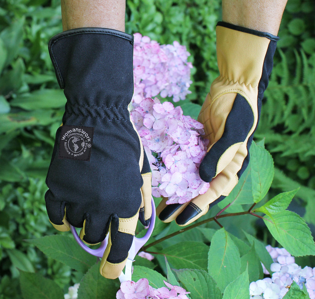Gardening gloves in yellow and black, worn hands among pink flowers