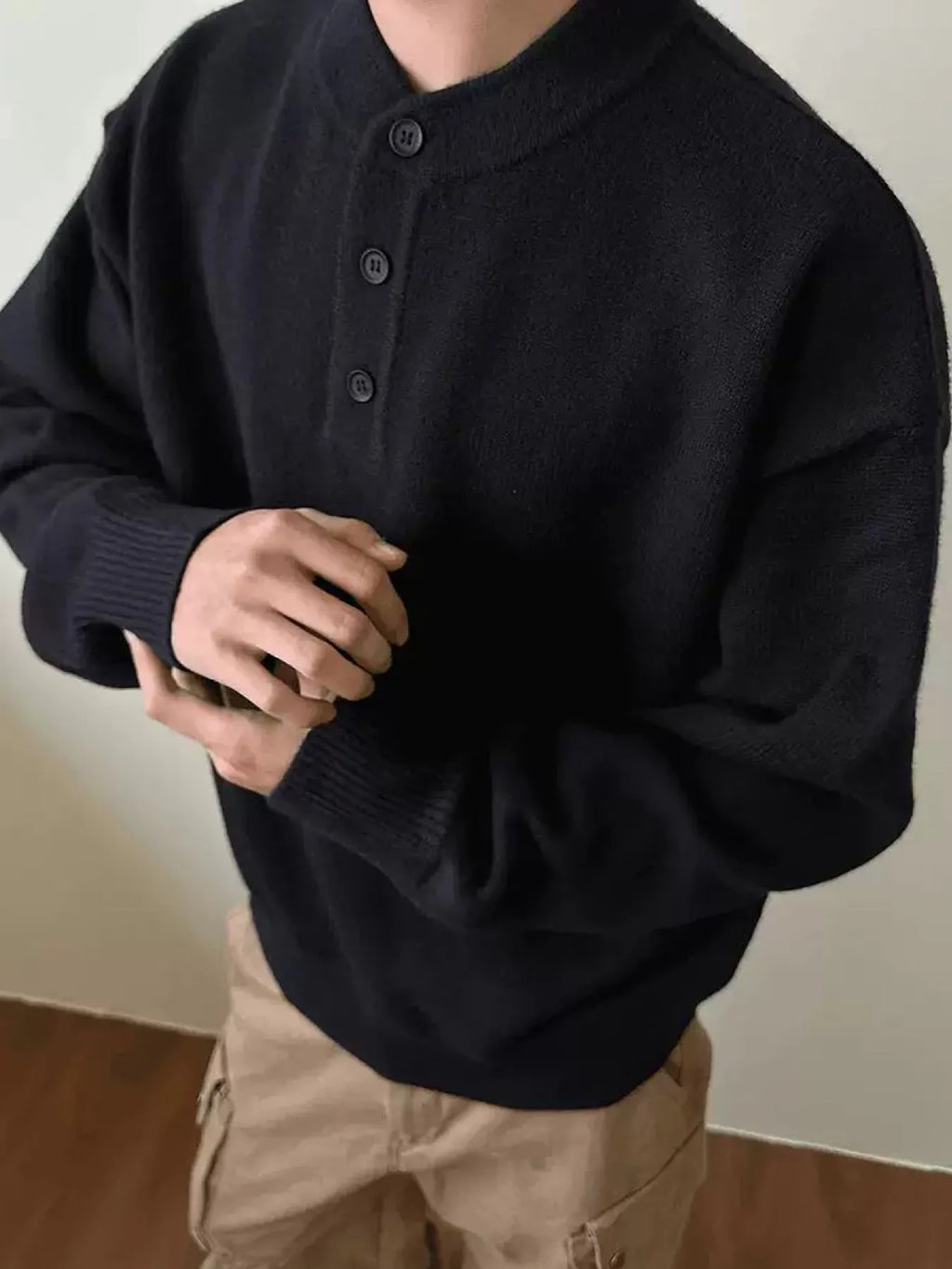 Black drop-shoulder knit sweater with three-button placket, ribbed cuffs and hem