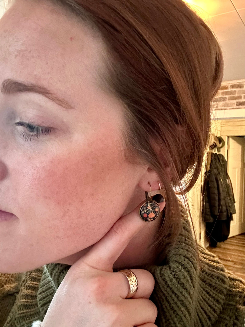 Close-up of round floral leverback earrings with orange blossoms and blue details.