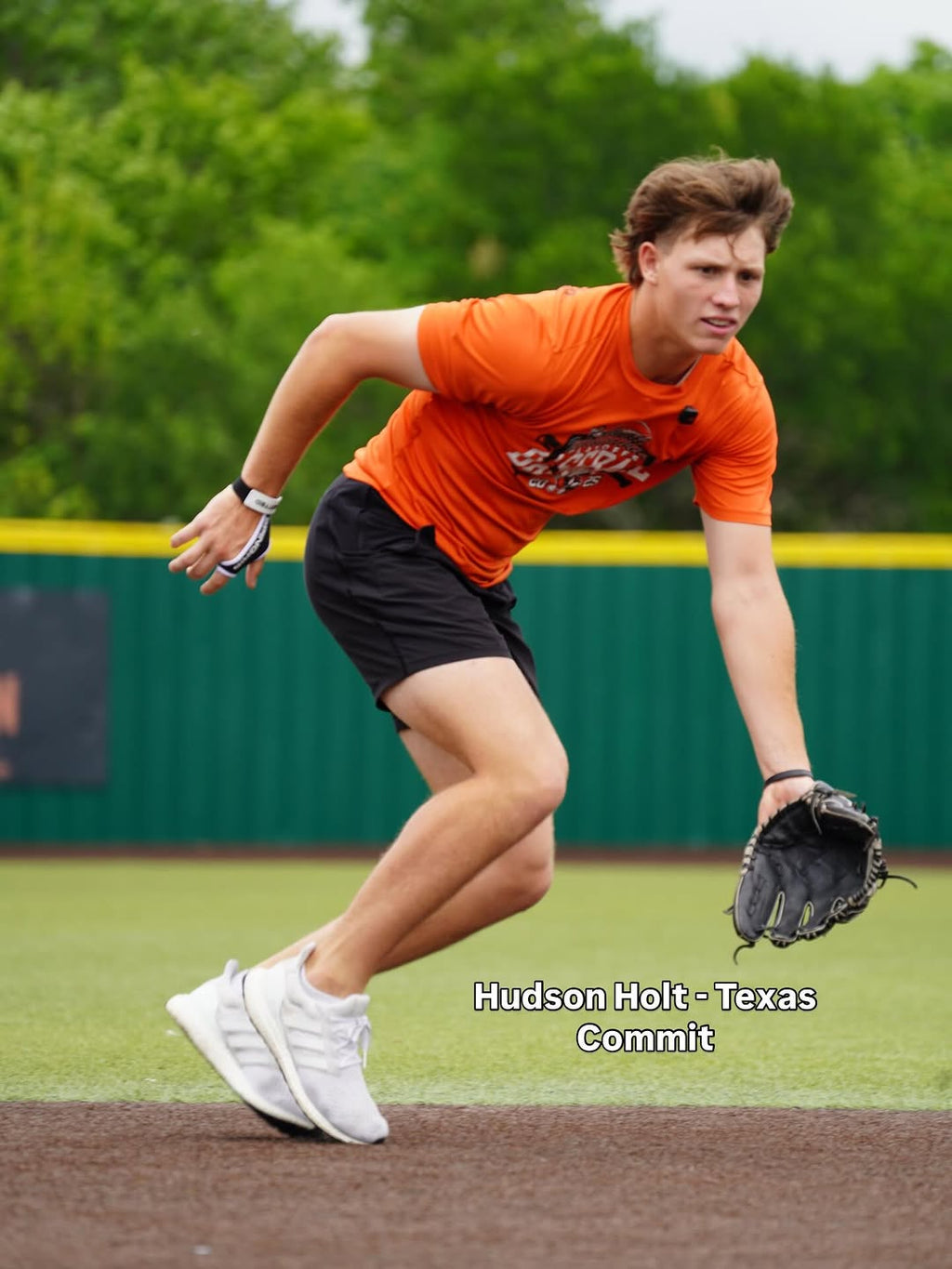 Baseball glove on player’s hand, black and orange with laced web