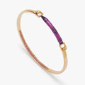 Gold-tone tension bangle with purple crayon-style center and engraved end clasps