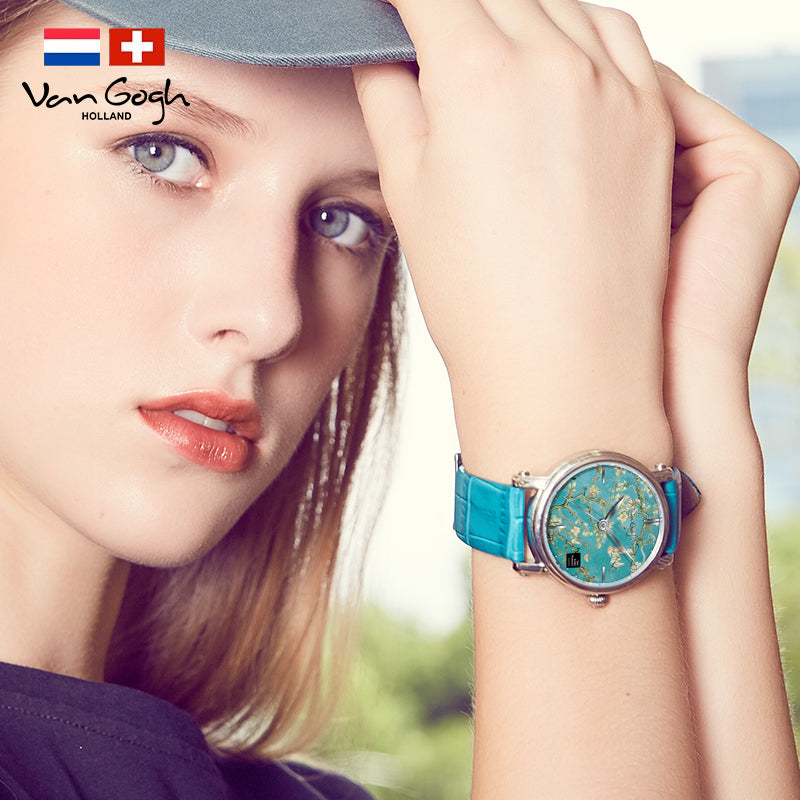 Women's quartz watch close-up on wrist with turquoise leather band and teal floral face.