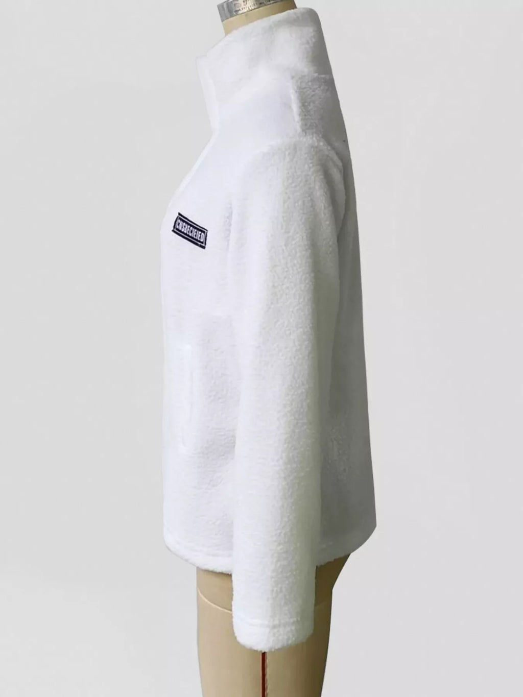 White sherpa fleece zip-up jacket side view with small logo patch