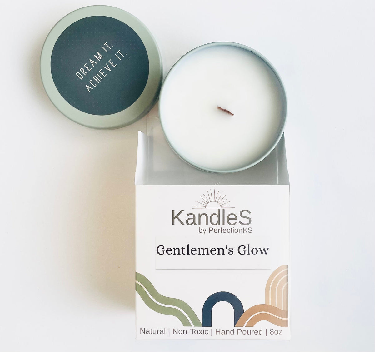 Soy candle in light sage tin; lid reads 'DREAM ACHIEVE IT' beside gift box
