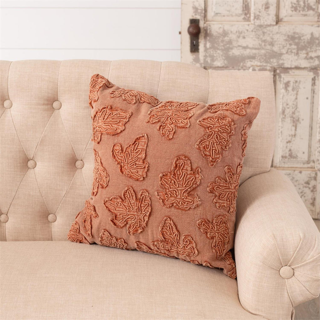 Orange stonewashed throw pillow with raised leaf embroidery, corner view, square