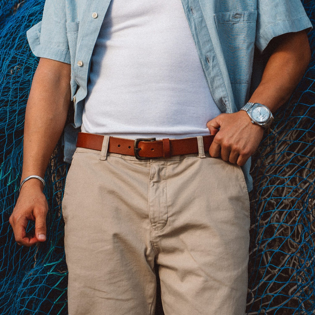Brown leather belt with metal buckle on tan pants