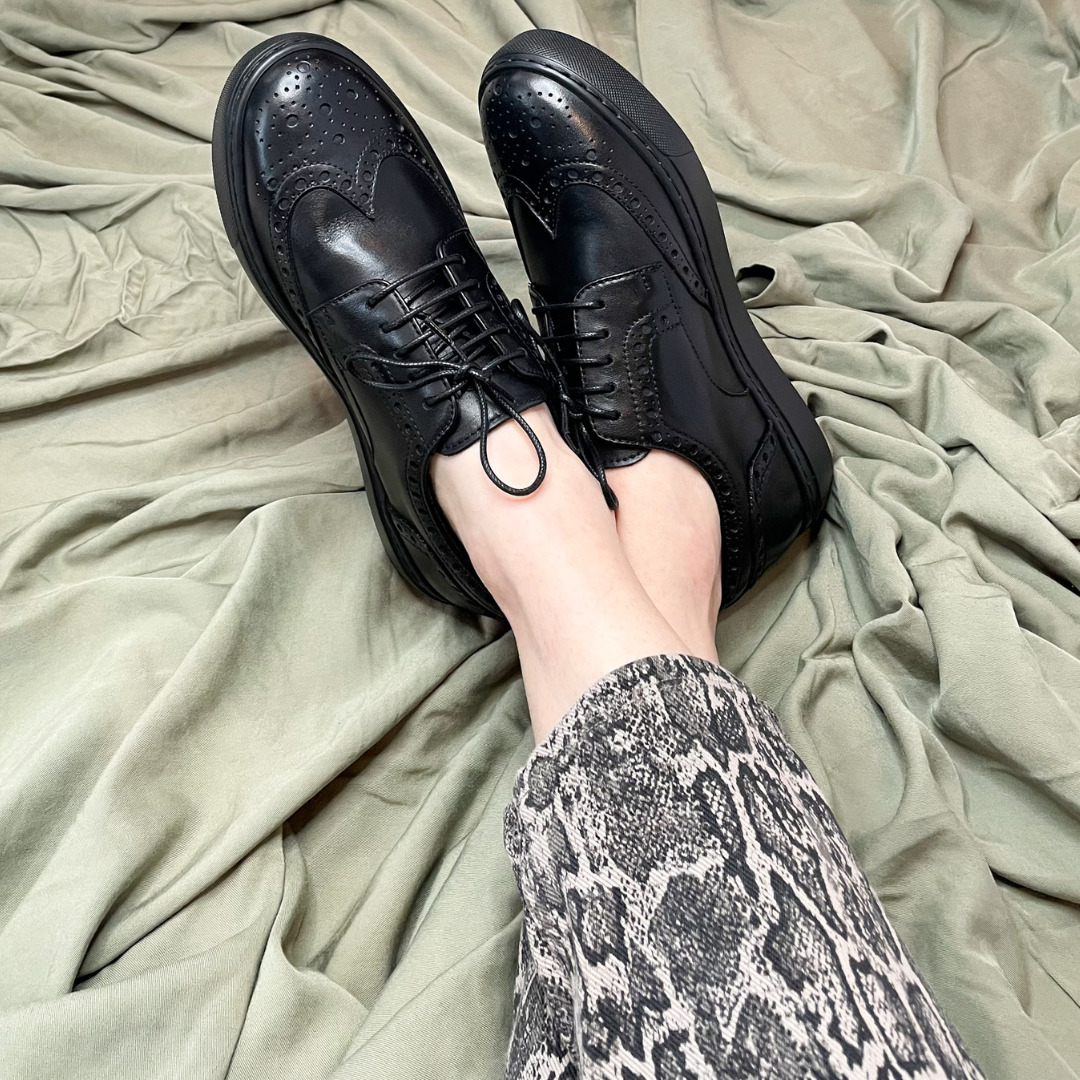 Black leather lace-up oxford shoes with perforated toe and textured brogue panels