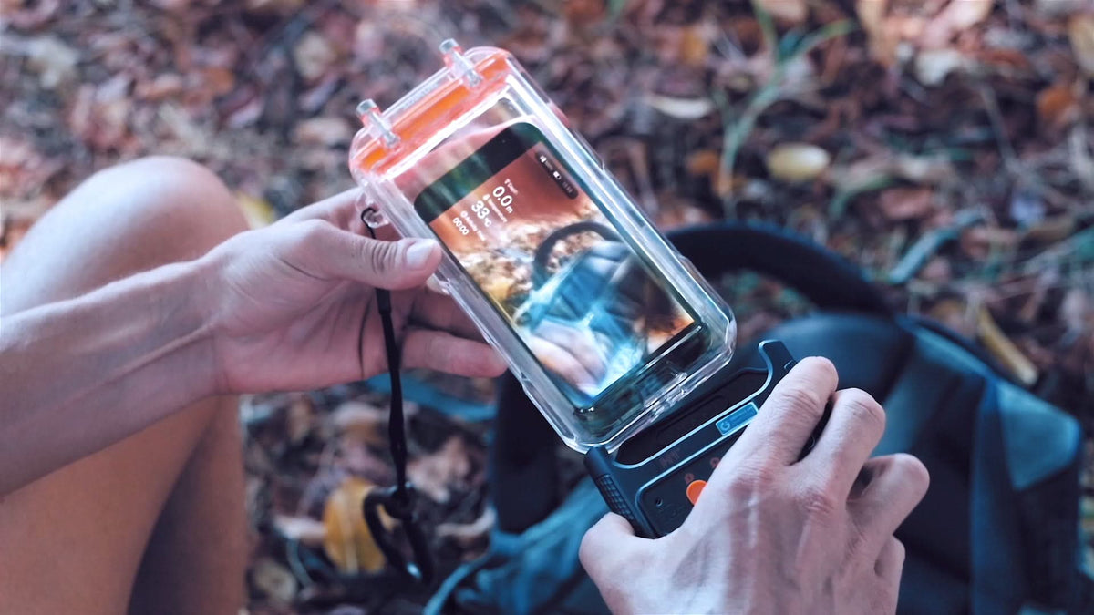 Waterproof phone case with clear orange cover, holding a smartphone outdoors.