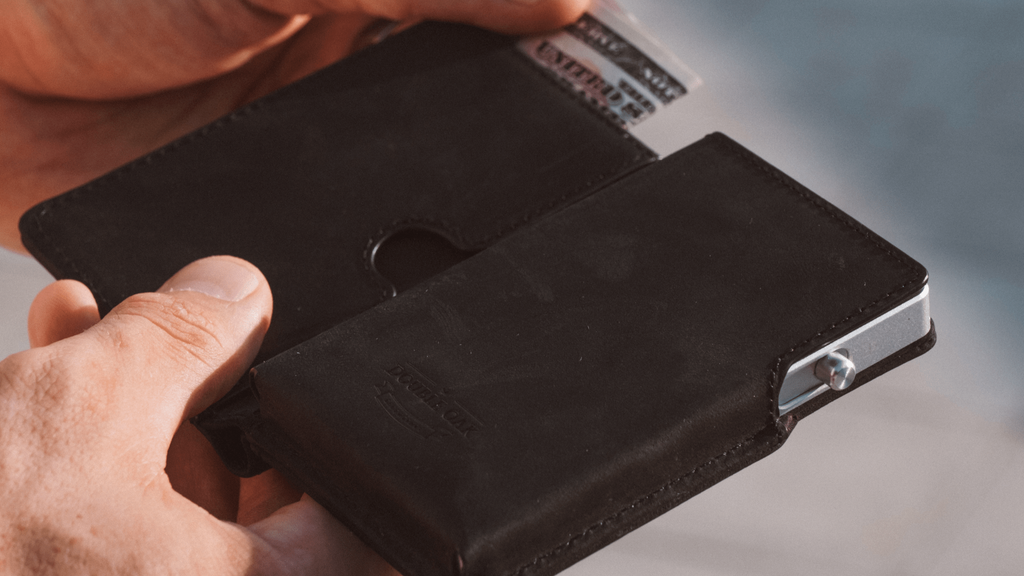Dark leather bifold wallet close-up with metal clasp and embossed logo
