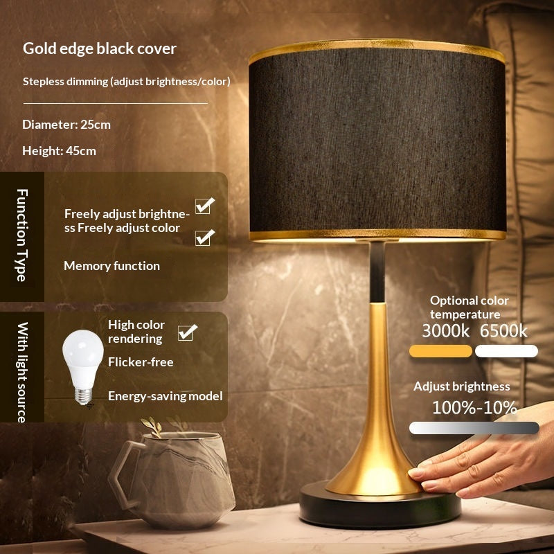 Gold table lamp with black fabric shade and gold base with dark round foot