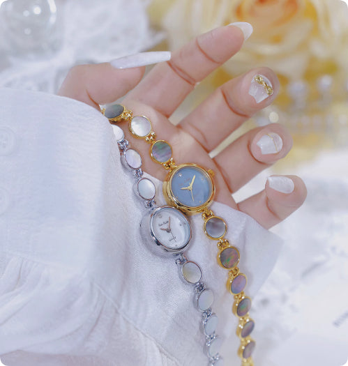 Gold and silver watch bracelets on open palm, featuring round dials and oval links