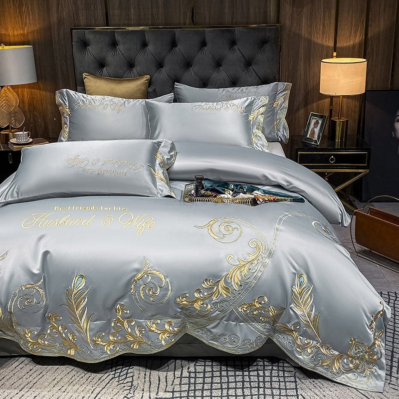 Gray quilted bed sheet set with gold and blue ornate embroidery and matching pillowcases