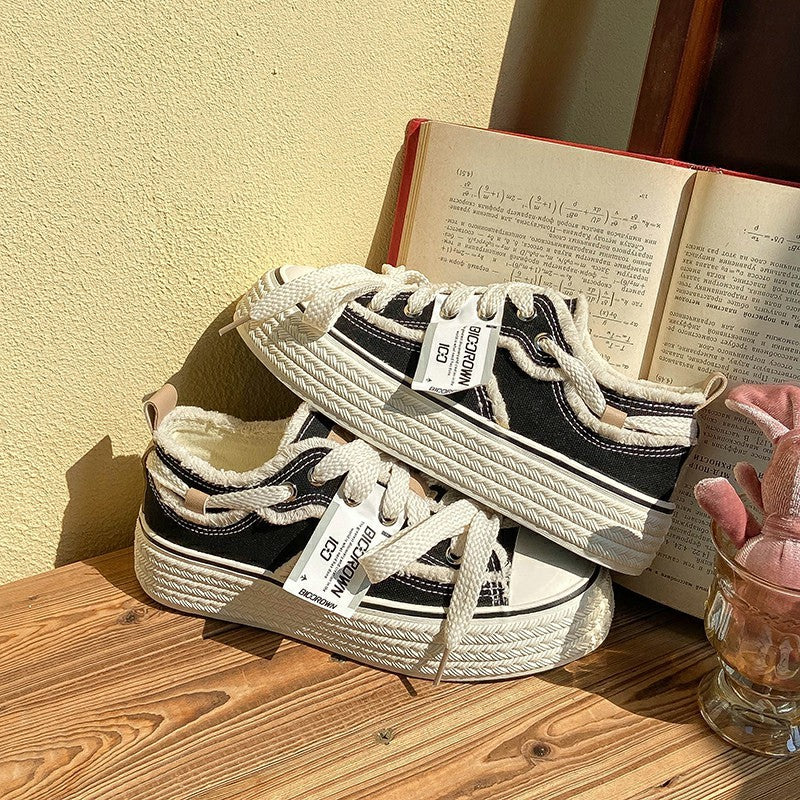 Pair of black low-top canvas sneakers with white laces and textured rubber sole.