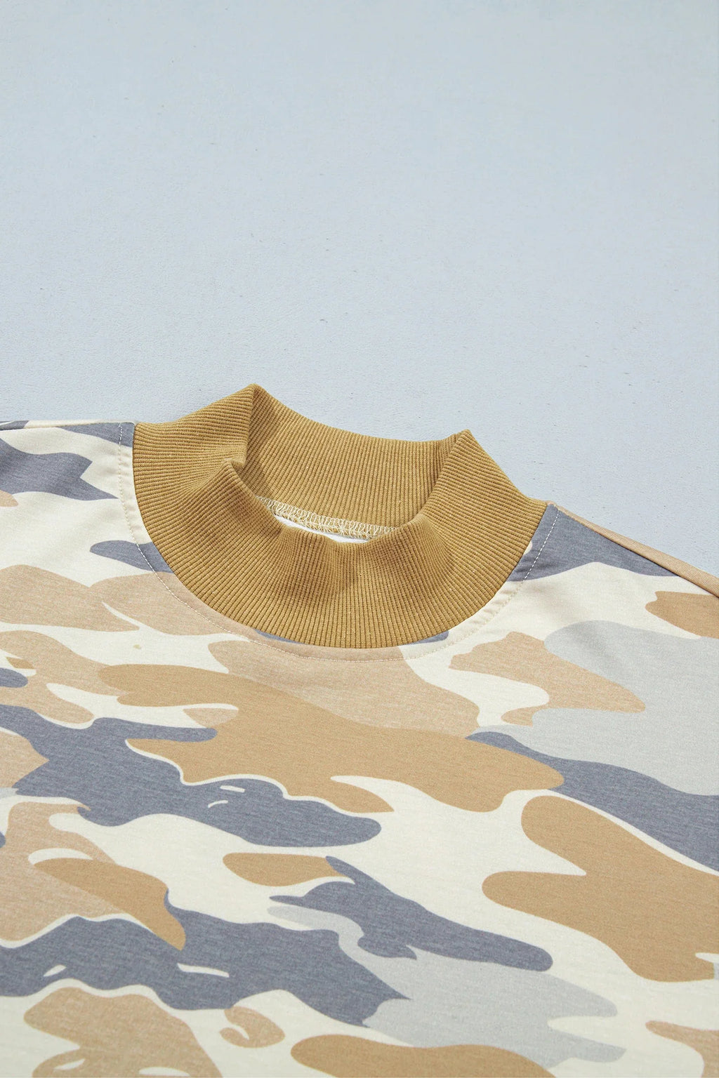 Camo mock neck top close-up with ribbed mustard collar and long sleeves