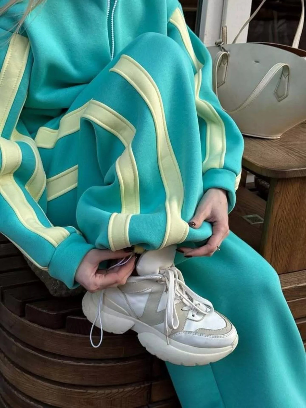 Teal zip-up top and pants set with bold contrast stripe trim at sleeves and cuffs.