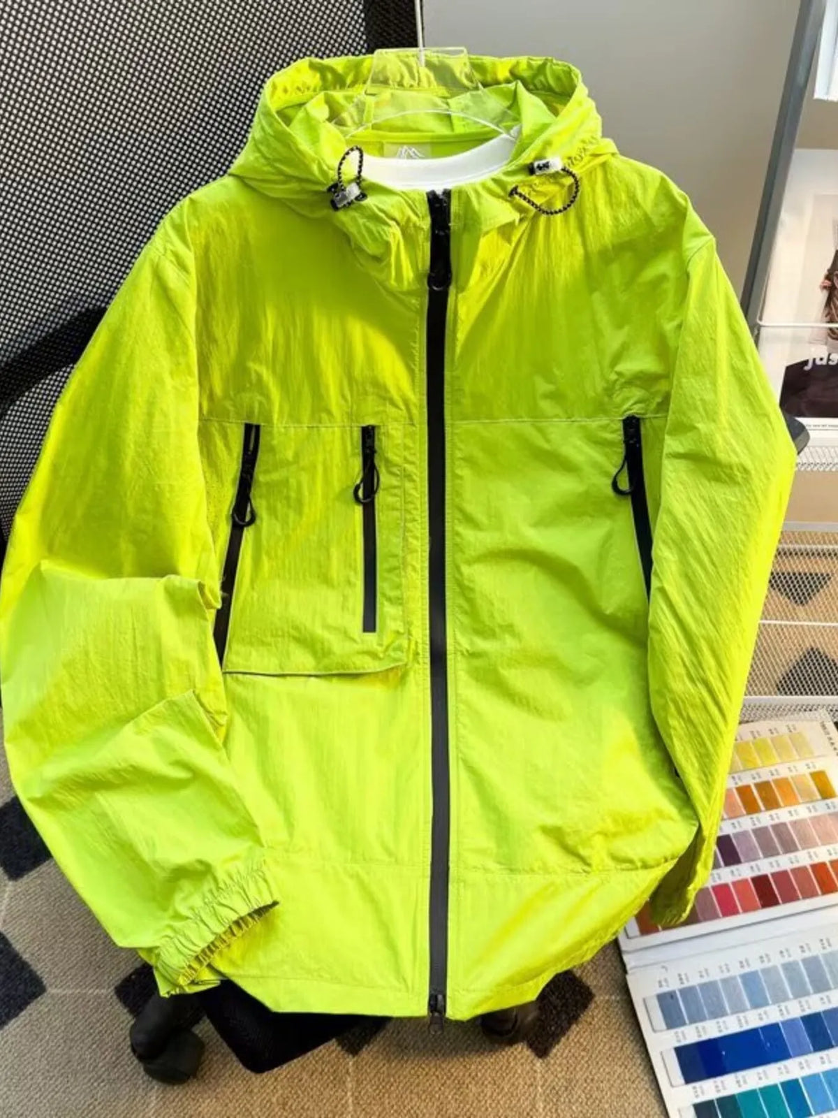 Lightweight hooded windbreaker jacket in neon yellow-green with full zip and flap pockets