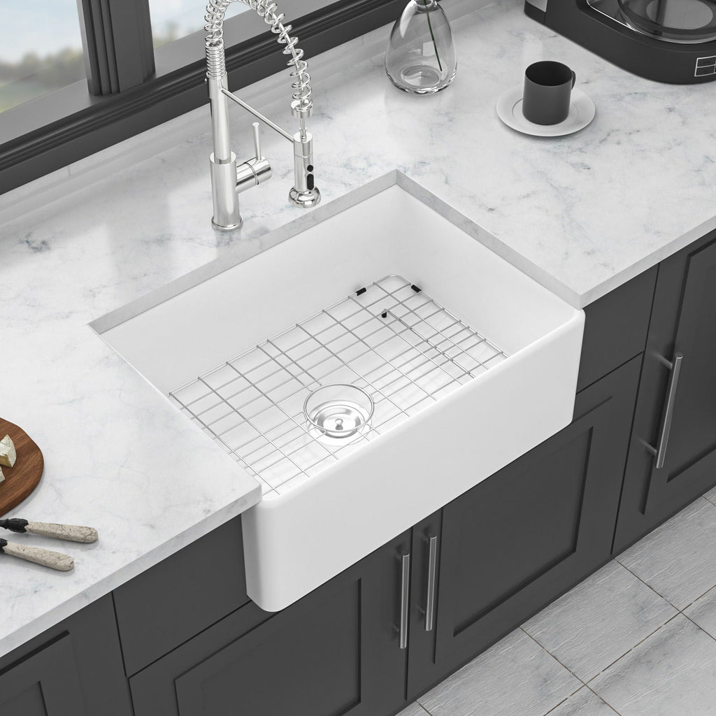White ceramic single-bowl apron-front sink with rack grid and drain opening