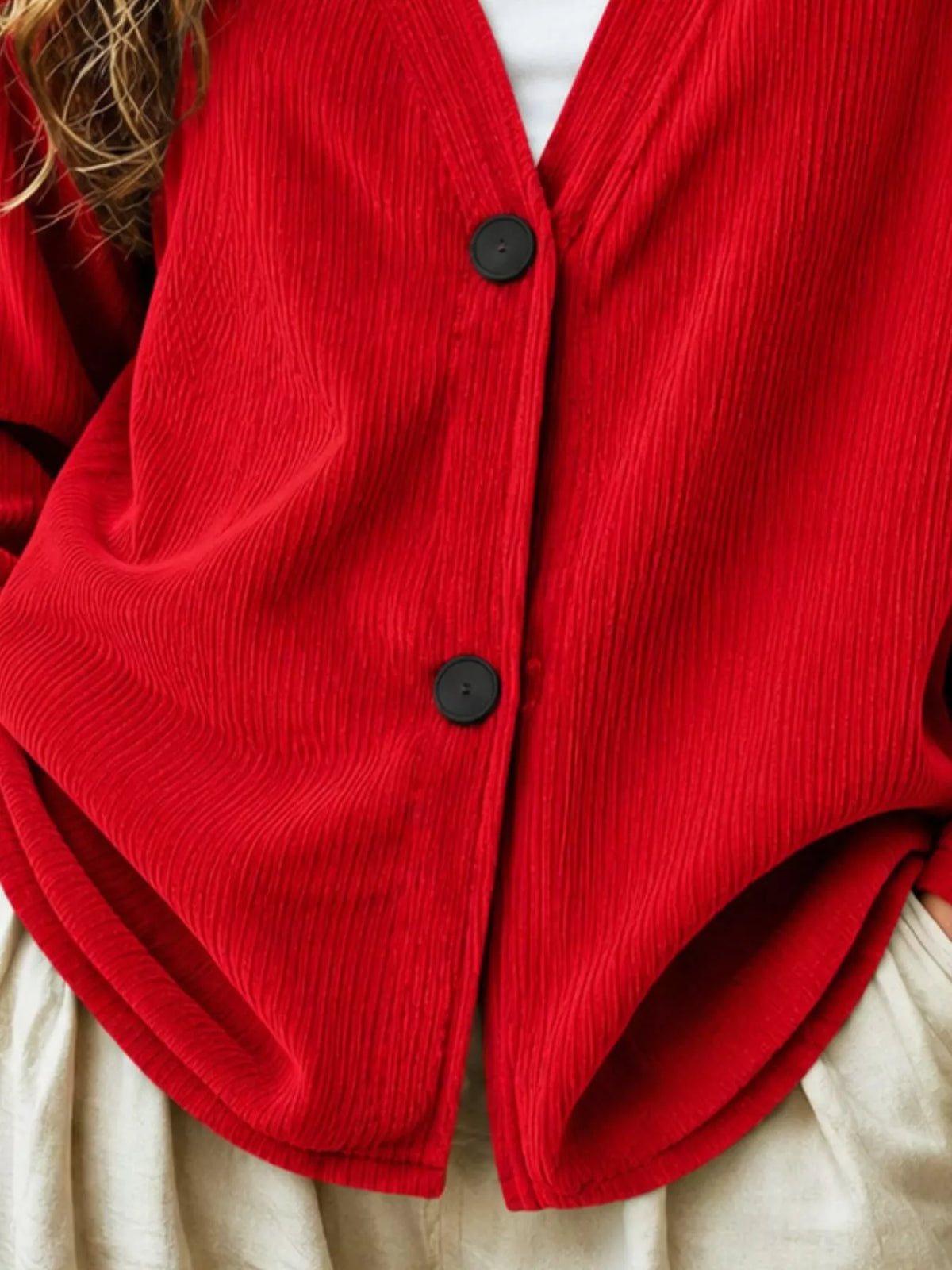 Red corduroy cardigan close-up, V-neck button front, two dark buttons