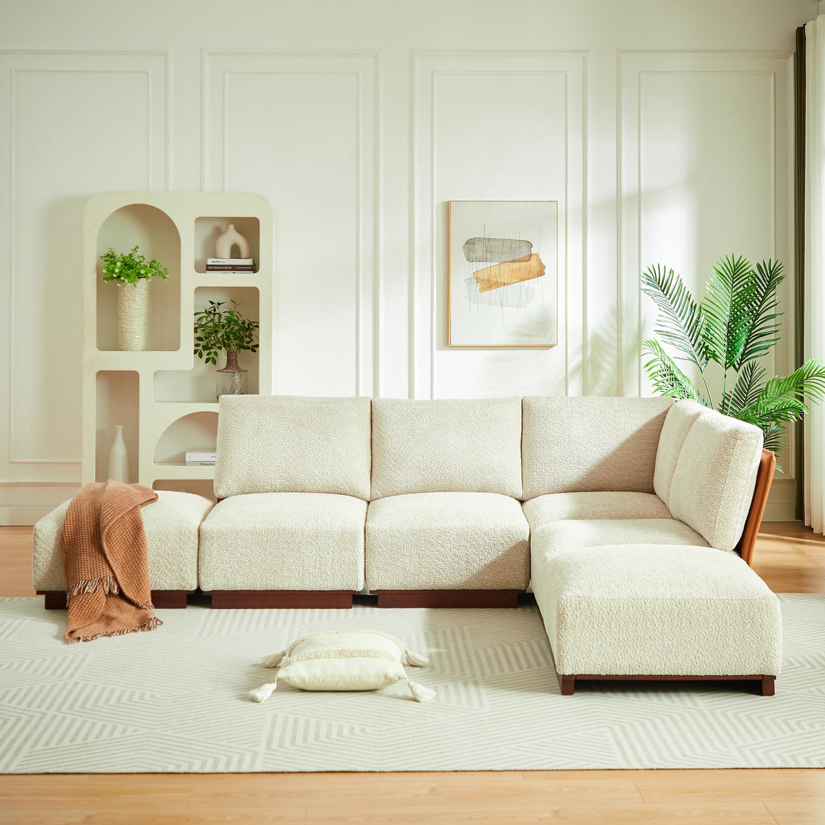 Sesame boucle sectional sofa with chaise modules and a folded terracotta throw