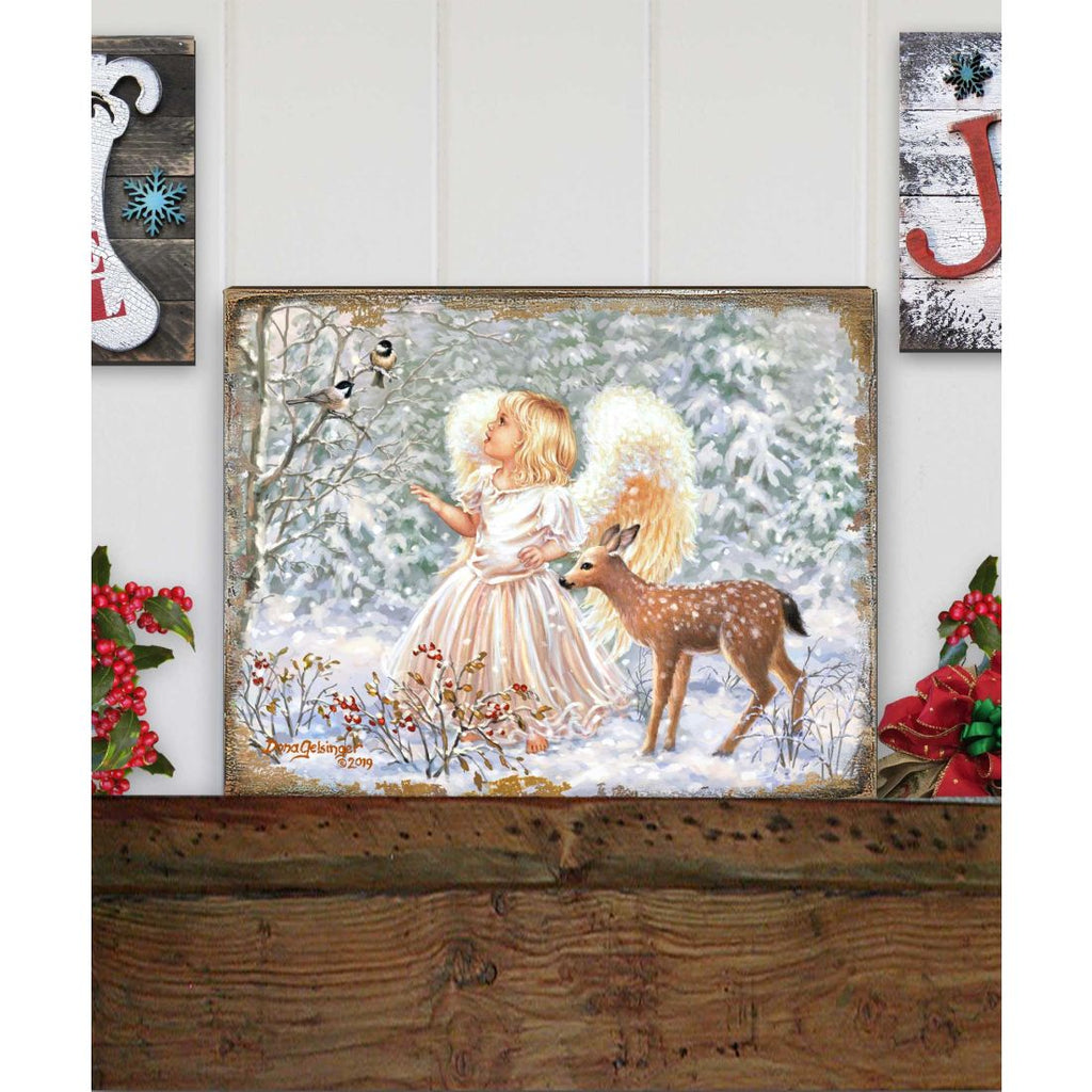Framed wooden wall art displayed on a wooden ledge with angel and deer in snow