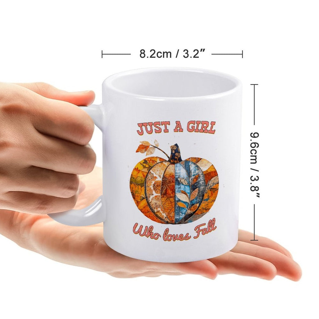 White ceramic mug with handle and pumpkin graphic, held by hands
