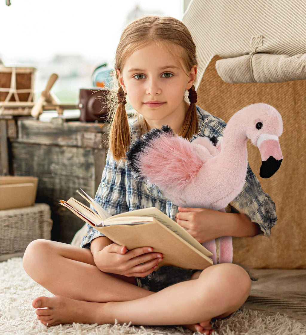 Flamingo plush toy resting on lap; soft light-pink body with black beak and dot eyes