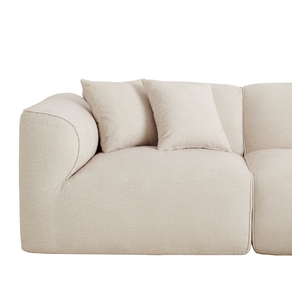 Single seat arm close-up of light beige sectional sofa with two throw pillows
