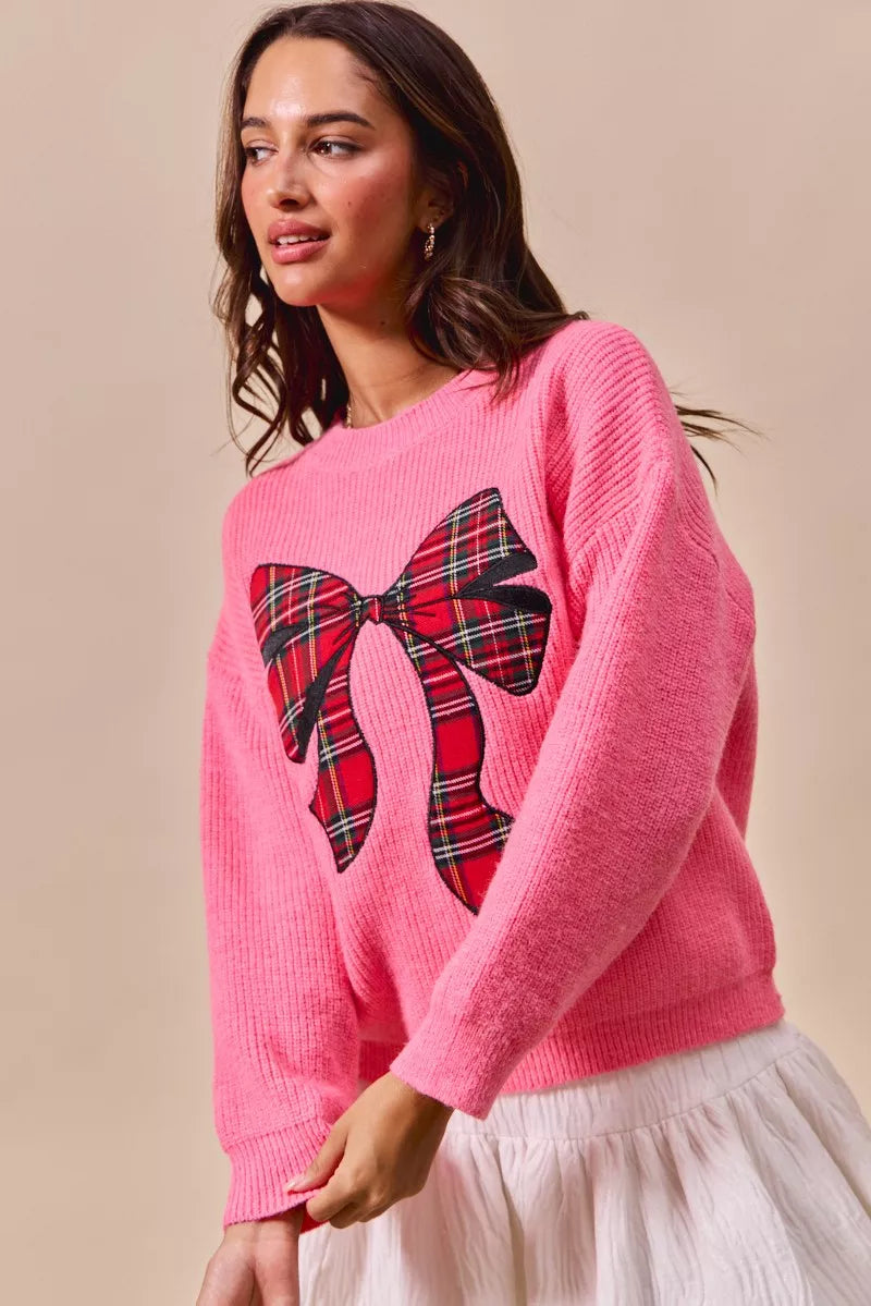 Pink sweater with a large plaid bow graphic on the front