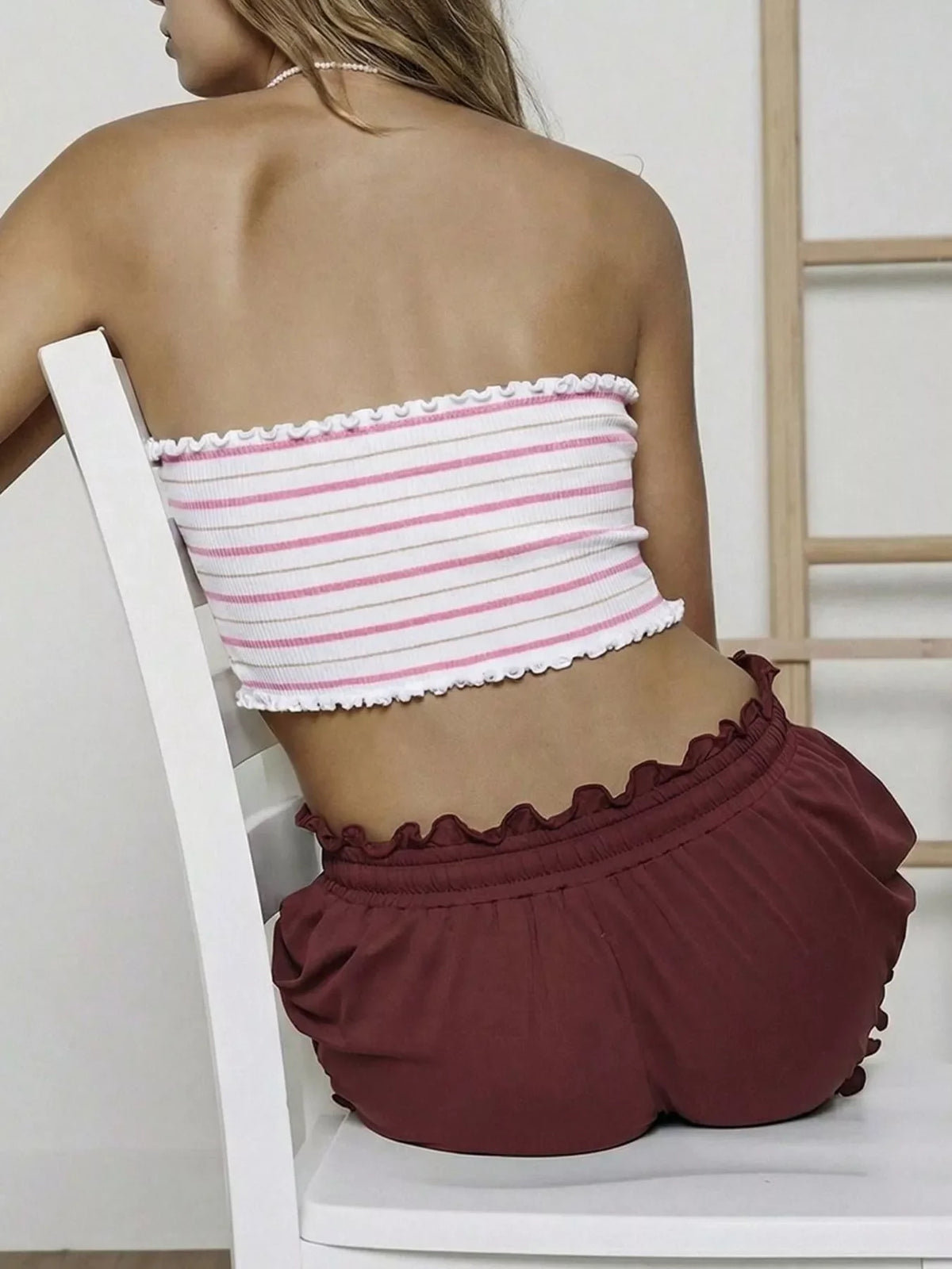 Back view of pink striped tube top with white ruffled hem and elastic finish