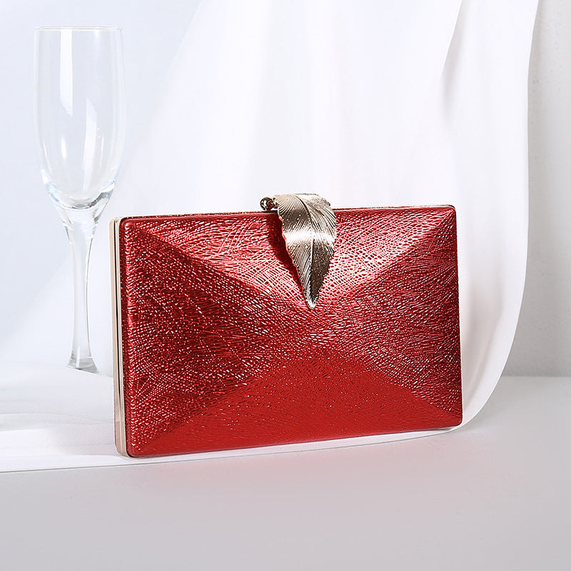 Red textured small evening crossbody bag with gold-tone bow clasp.